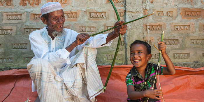 Un grand-père fabrique un arc et une flèche en bambou et montre à son petit-fils comment les utiliser. 