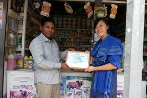 me presenting a certificate of training to one of the shop owners in CARE Bangladesh's social enterprise called Krishi Utsho