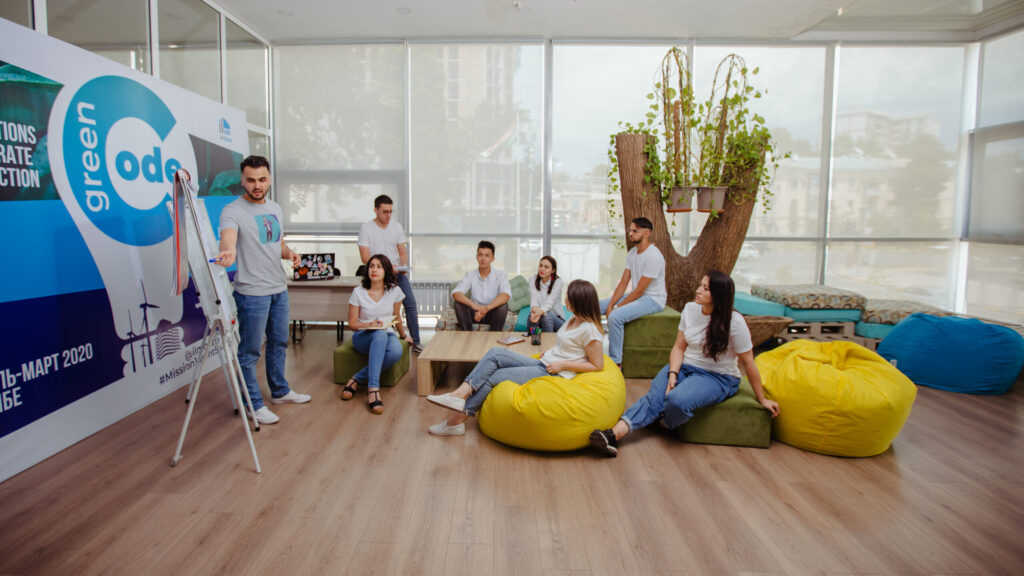 Eight people are having a meeting in a bright, well-lit room. 