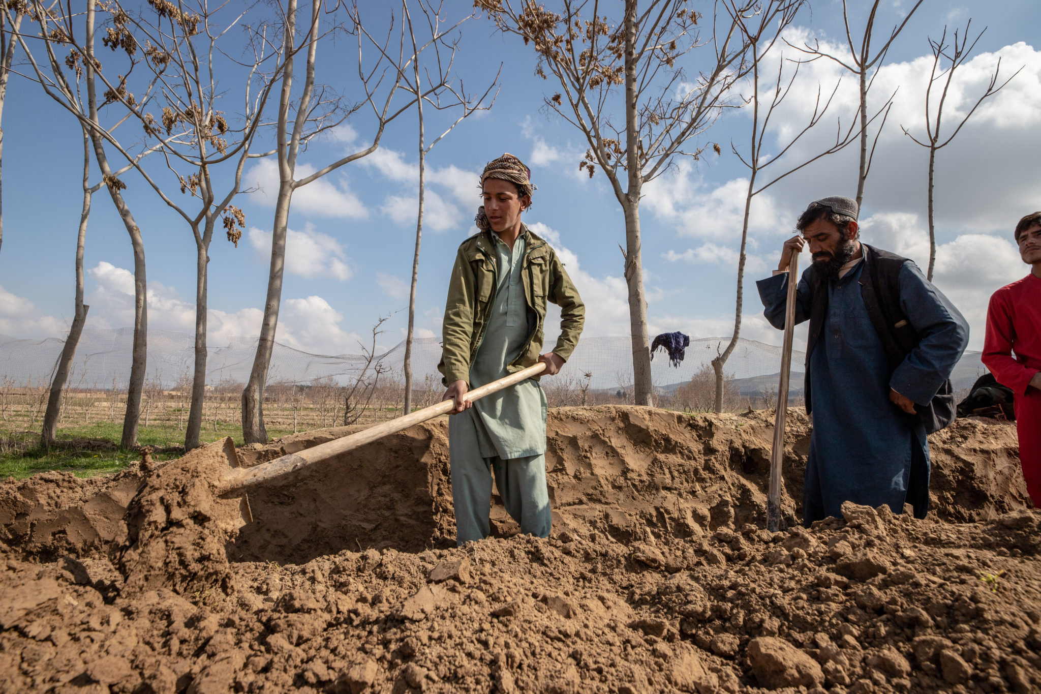 An person holding a shovel, is digging in a field.