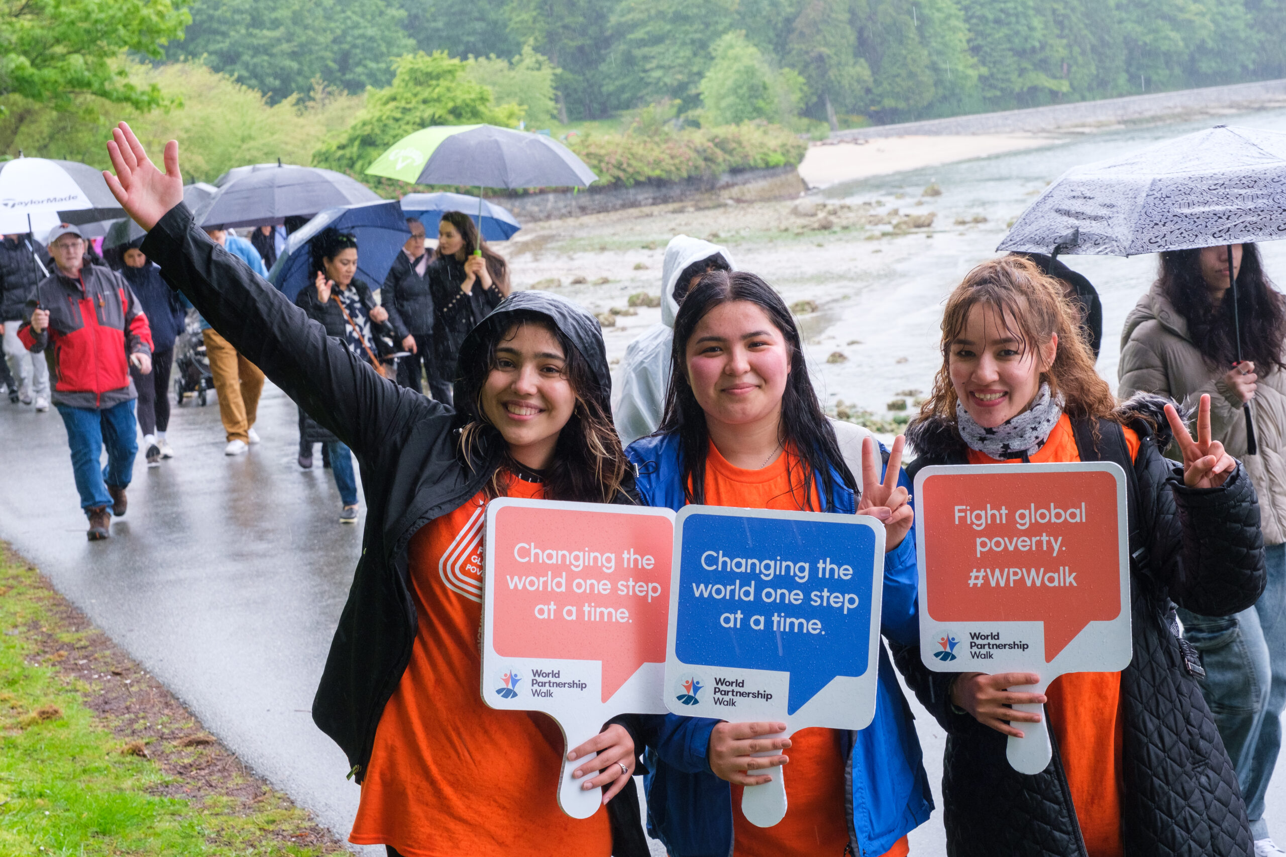 Three young people hold up posters reading "Changing the world one step at a time."
