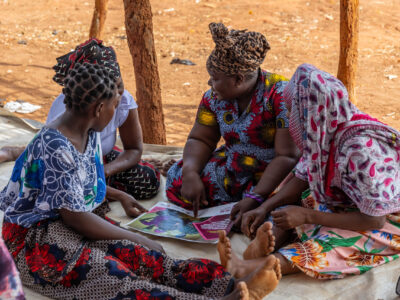 Caption: Fatima Fernando, a Women's Change Group Influencer, discusses issues raised in the printed material with fellow attendees of the session.

Location: Nanhupo Village, Montepuez

Country: Mozambique

Project: SPARC

Institution: Aga Khan Foundation Canada